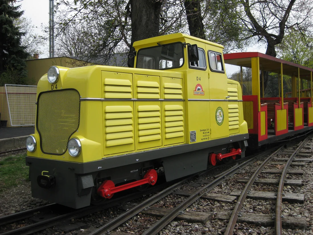Gelb-rote Diesellokomotive D4 001 der Liliputbahn im Wiener Prater auf einem schmalspurigen Gleis.