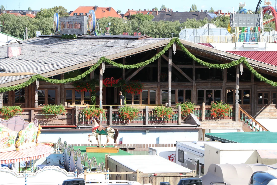Westseite der Käfer Wiesn-Schänke auf dem Münchner Oktoberfest mit traditioneller Holzfassade und gemütlicher Biergarten-Atmosphäre